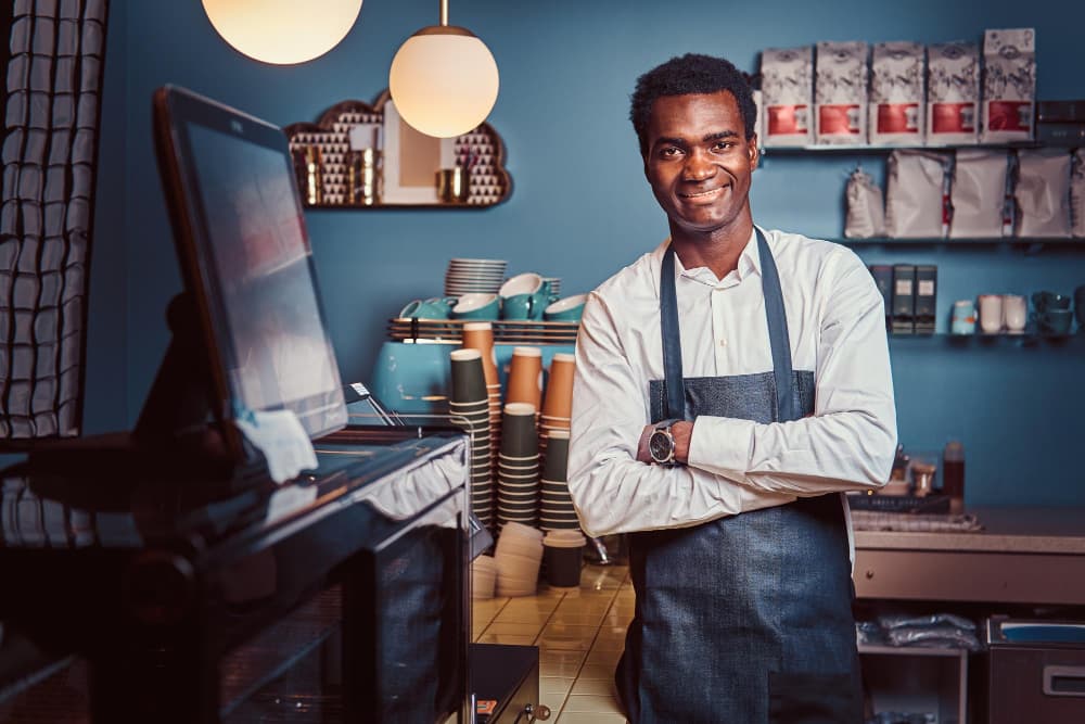 portrait handsome african barista standing with crossed arms counter trendy coffee shop